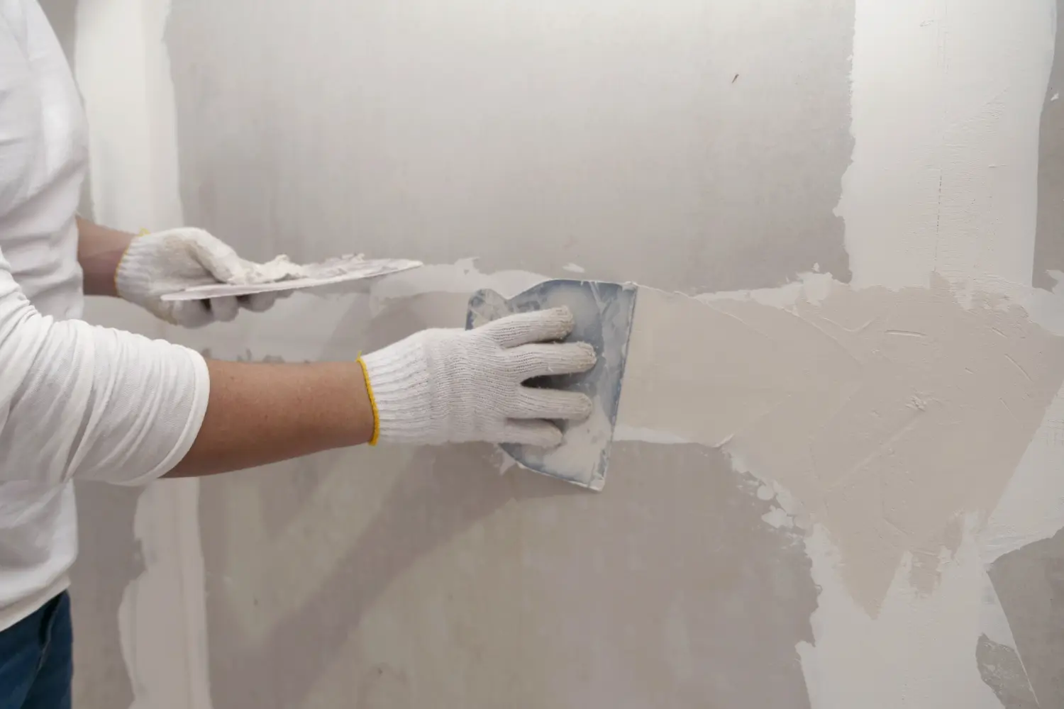 Vorbereitung von Gipser- und Wandanstricharbeiten. Asiatischer Mann füllt Trockenbaustellen aus.